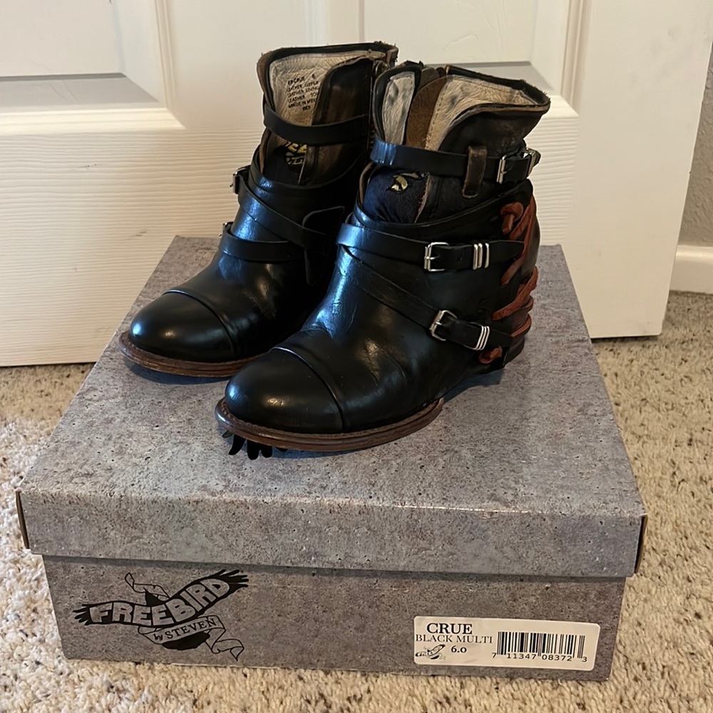 Black booties with buckles and red details on the heel.